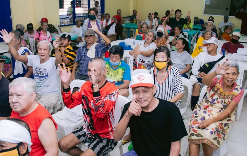 A group of elderly celebrating while sitting in white chairs.