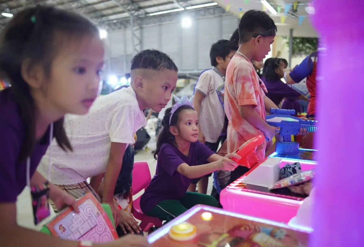 Children playing with arcade machines brought in by the MOD Movement.