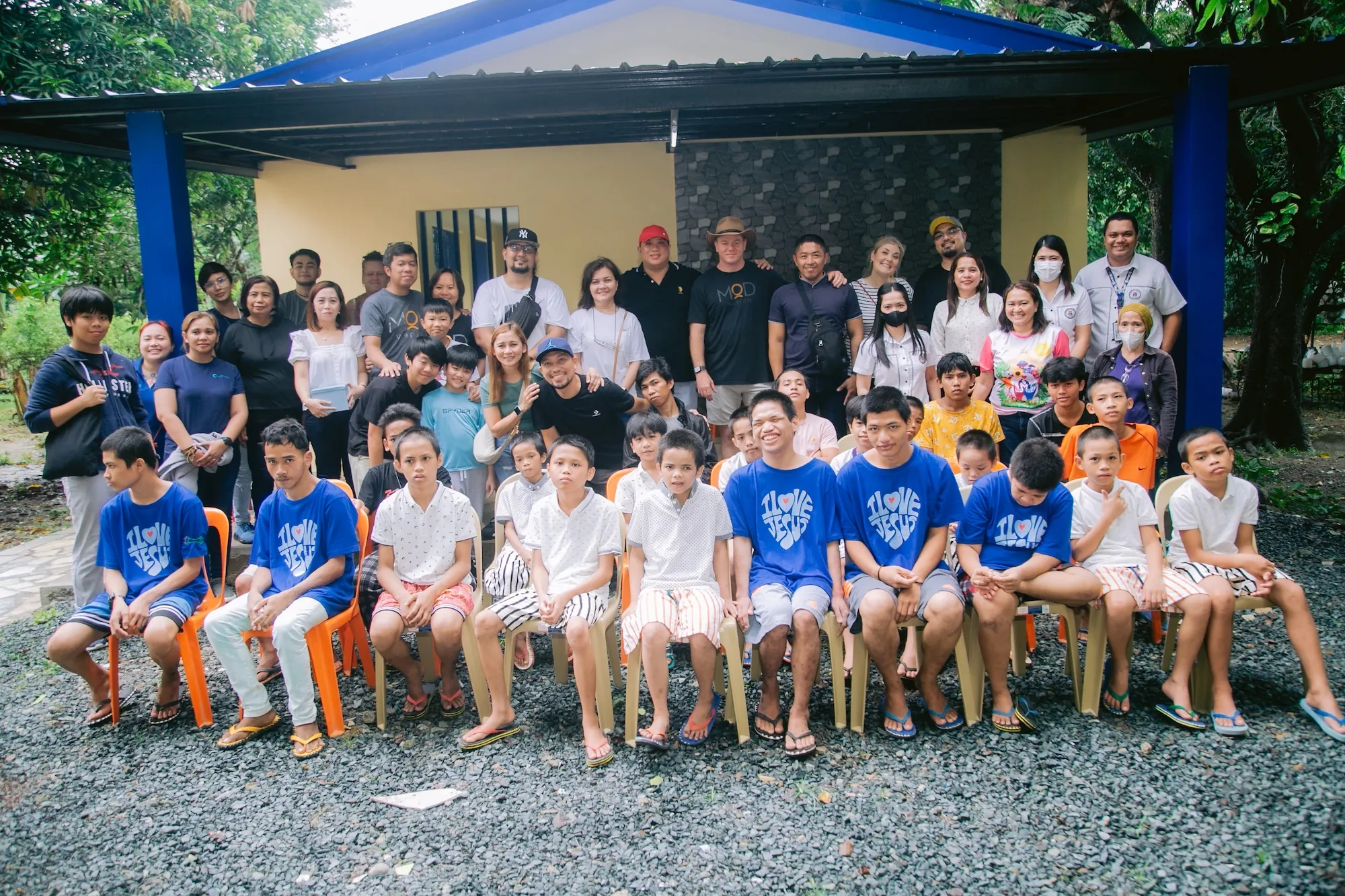 A group photo of young men and women taken in front of a newly built building.