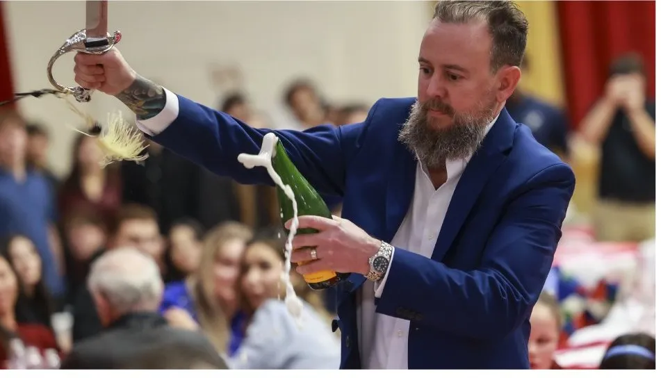 The auctioneer sabering a bottle of champagne during the live auction